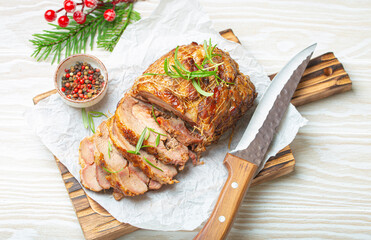 Christmas rolled turkey roasted with spices and herbs on baking paper with knife and wooden white background top view. Baked cut for slices turkey fillet roll for festive Xmas dinner.