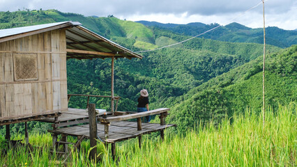 Rear view of a woman sitting on wooden terrace and looking at a mountain view