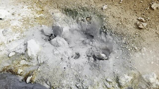smoking boiling and hissing mud pot with colorful sulferic crystals around it