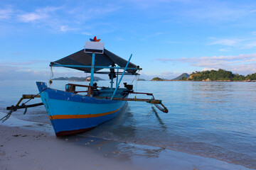 Obraz premium a small passenger boat is anchored on a clean beach with a background of ocean and a bright blue sky