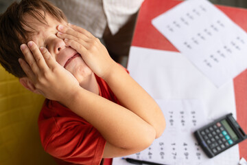 A child with dyscalculia and dyslexia is on the verge of tears while trying to complete his math homework.