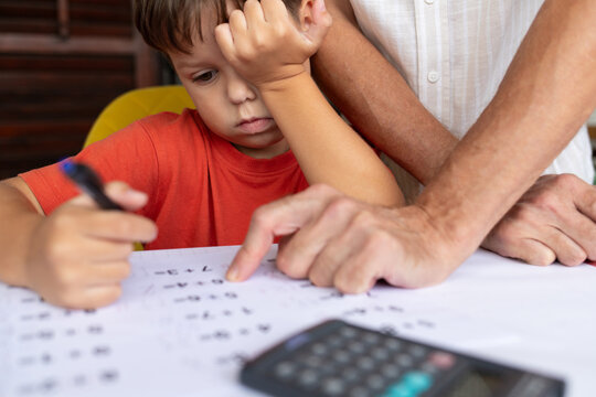 A father helps his 6-year-old son with his math homework. - Powered by Adobe