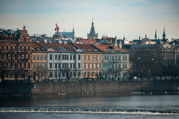 Obraz premium Historic architectural view along the Vltava River in Prague with buildings and towers under a clear sky