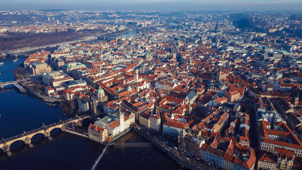 Fototapeta premium Aerial view of Prague showcasing historic architecture, bridges, and vibrant rooftops under clear blue skies