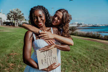 Two women are hugging each other and holding a sign that says 