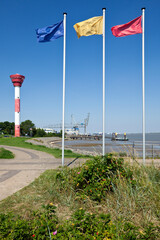 Nordenham, lighthouse and harbor on the Weser river, flagpoles in foreground