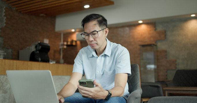 Businessman chatting on laptop. communication technology. Asian Middle-aged man using smartphone to shop online. Senior make financial transactions, transfer money via bank apps, order products.
