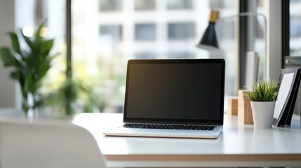 Fototapeta premium Close up view of portable workspace with laptop, stationery and plant pot o the table in co-working space 