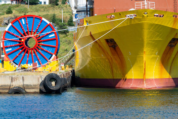 Bulk sub-sea industrial glass fiber optic cable on a metal spool on a ship's stand. The yellow data...