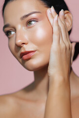 Beautiful close-up of a Latina woman with glowing skin and natural makeup, gently resting her hand...