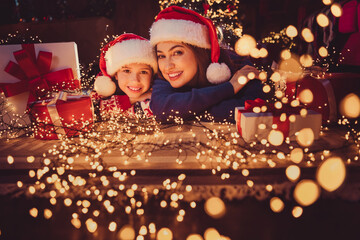 Portrait of two people mother daughter lying floor toothy smile festive christmas time illumination flat indoors