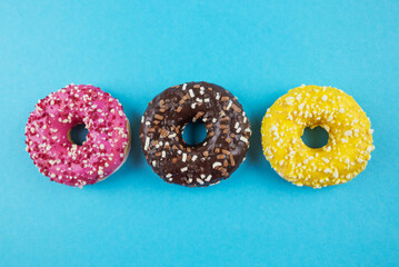 Three donuts with different glazes on a blue background