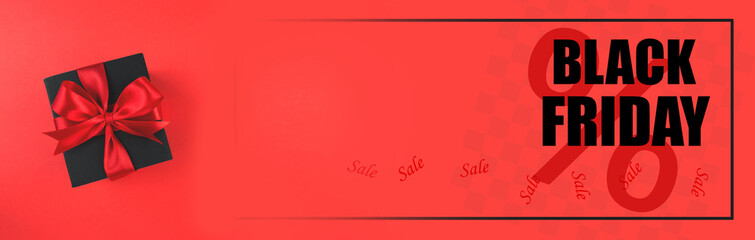 Black Friday sale concept. Black gift box with red satin ribbon on red background. Copy space. Banner.