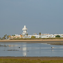 sand beach at Isla Christina at the Costa de la Luz in Andalusia with view to town and lighthouse