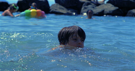 Boy swimming in lake, face close to water, captured in slow-motion at 800 fps, summer fun, playful...