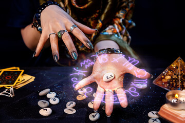 The fortune teller holds a rune with a luminous astrological circle above it in the palm of her hand. The concept of divination, astrology and predicting the future