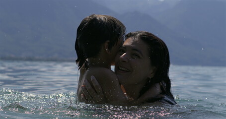 Mother and son embracing in the lake in slow motion at 800 fps, sharing laughter and joy on a sunny...