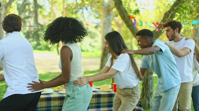 Group of friends playing conga line at birthday party
