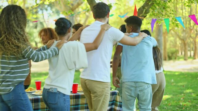 Group of friends playing conga line at park party
