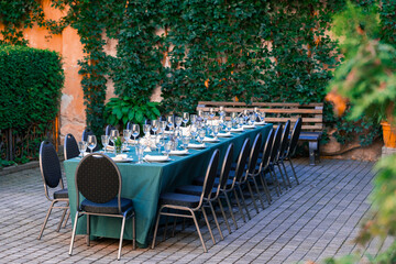 served table with dishes cutlery and drinking glass outdoor cozy back alley garden outdoor spring place without people here ready for some event