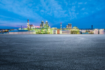 Empty asphalt road and petrochemical plant industrial buildings at night