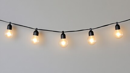 A string of warm white lights illuminates elegant bulbs suspended against a neutral grey backdrop, enhancing any setting with a cozy and inviting atmosphere