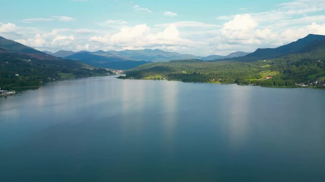 Aerial perspective of Colibita Lake, Romania. Colibita is an artificial accumulation lake on the Călimani mountains, county Bistriţa-Năsăud. Green landscape. Forest. Drone panning right. Travel.
