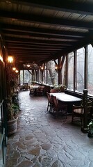 Fototapeta premium Stone patio with wooden beams and tables, with a view of the woods through the windows.