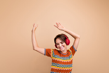 Portrait of pretty positive person beaming smile closed eye enjoy music headphones dance isolated on beige color background