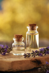 Two bottles of aromatherapy essential oil with fresh lavender flowers outdoors