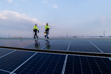 Engineers walking on roof inspect and check solar cell panel by hold equipment box and radio...