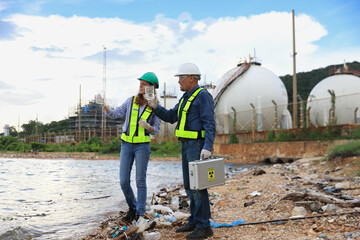 A senior couple of environmental engineers are hard at work outdoors, analyzing and collecting wastewater samples in an industrial area.