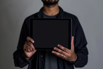 Ui mockup indian man in his 20s holding a tablet with a completely black screen