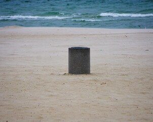 Kosz na śmieci na środku plaży. W tle fale na morzu. © Adam