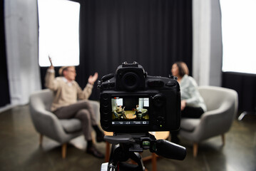 A middle-aged journalist engages in a professional interview with a specialist in a contemporary...
