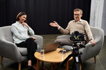 A middle aged female journalist engages with a male expert in a professional interview atmosphere.
