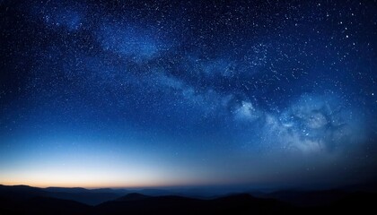 Fototapeta premium Expansive Night Sky Over Mountainous Horizon with Thousands of Stars Illuminating the Deep Blue Twilight, Capturing the Serene Transition from Dusk to Dawn in a Vast and Tranquil Wilderness