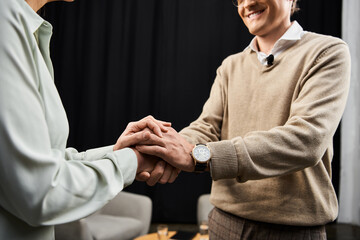 A journalist warmly shakes hands with a specialist during an insightful dialogue in a modern studio.