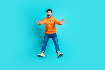 Photo of worried nervous man wear trendy clothes jump up isolated on cyan color background