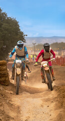 Two motocross riders fighting to get ahead and escape from other riders on an outdoor dirt track creating a lot of dust with their knobby tires.