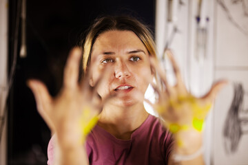 A creative female painter in her studio, with vibrant yellow paint on her hands, focusing intently...