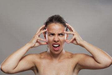 Fototapeta premium Young woman in distress with hands on temples showing strong emotions