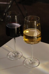 Two wine glasses, one red and one white, sit on a table