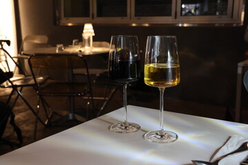 Two wine glasses, one red and one white, sit on a table
