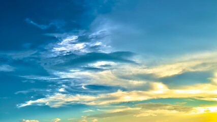 Obraz premium Two-tone sky photo with beautiful clouds in shape, light orange and blue sky background, white clouds reflecting the evening sunlight.