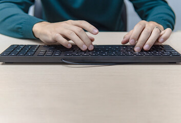 Close up businessman hands using a computer in the office, front view, typing the keyboard, business concept