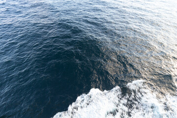 Top-down view of churning water cascading away with a bit of white foam cascading outwards towards the bottom.