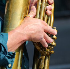 hands of the player while setting the notes on the brass wind instrument during the performance