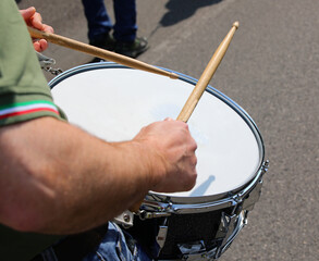 drummer with wooden sticks while marching with the band through the streets