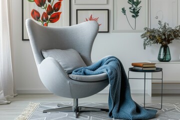 Modern Gray Fabric Egg Chair with Stainless Steel Base, Botanical Prints, Books, Blue Blanket in Contemporary Living Room Design